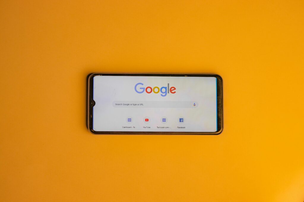 Google Search Engine on phone, portrait, against orange background